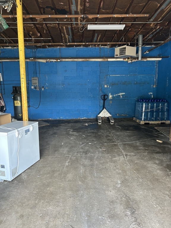 Basement with blue-painted block walls, exposed ceiling, concrete floor, and a chest freezer.