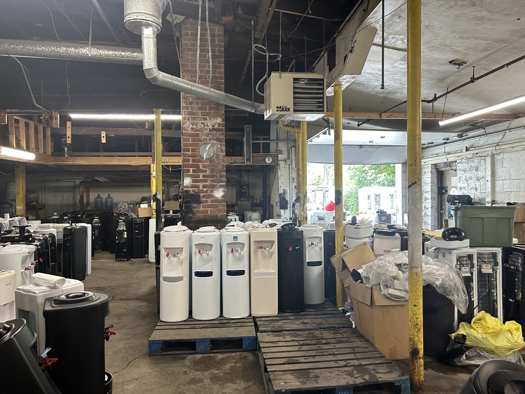 Industrial interior filled with water dispensers, exposed brick, ductwork, and yellow support columns.