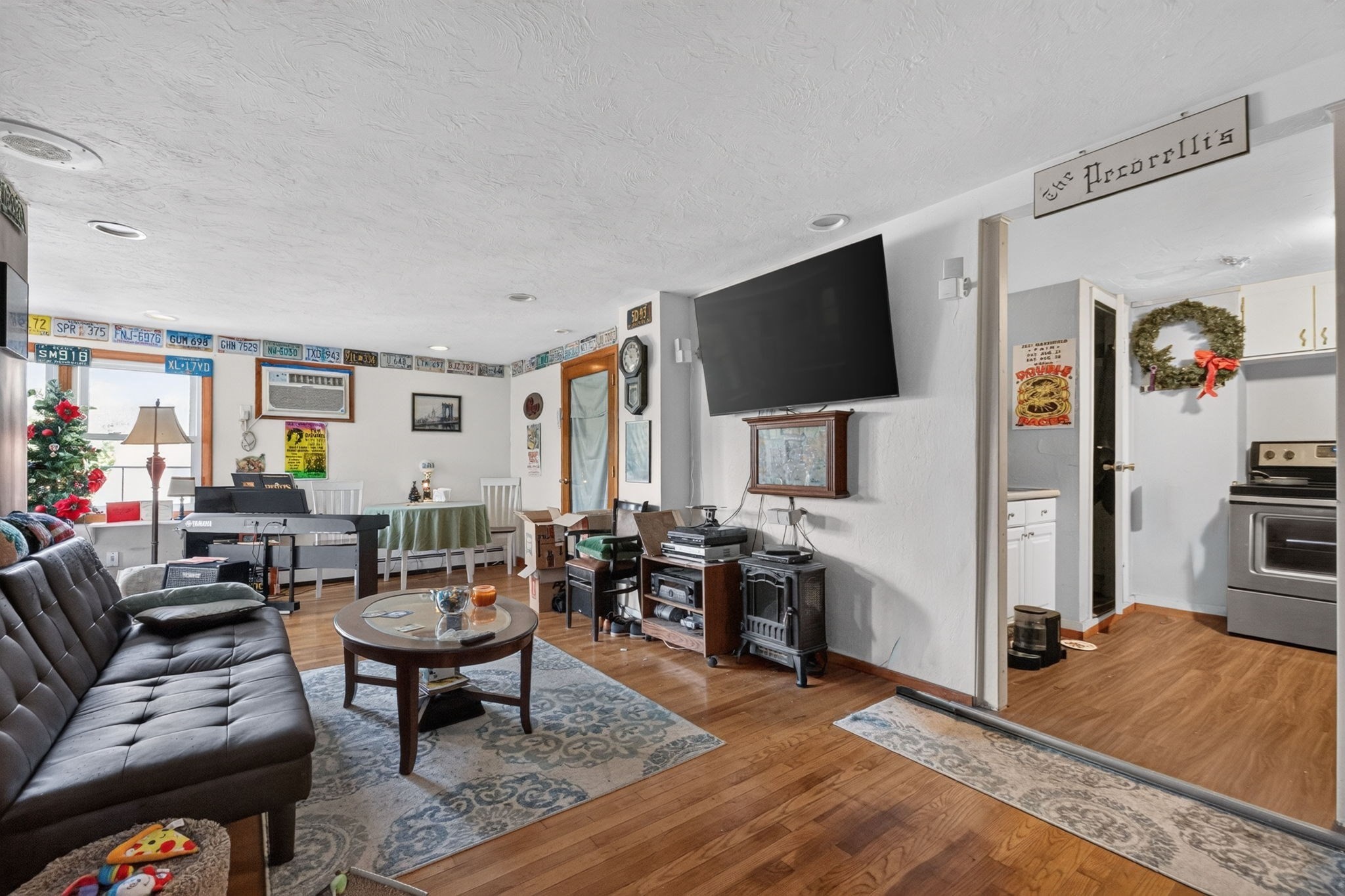 Living room with a leather sofa, hardwood floors, and a dining area beside the kitchen.
