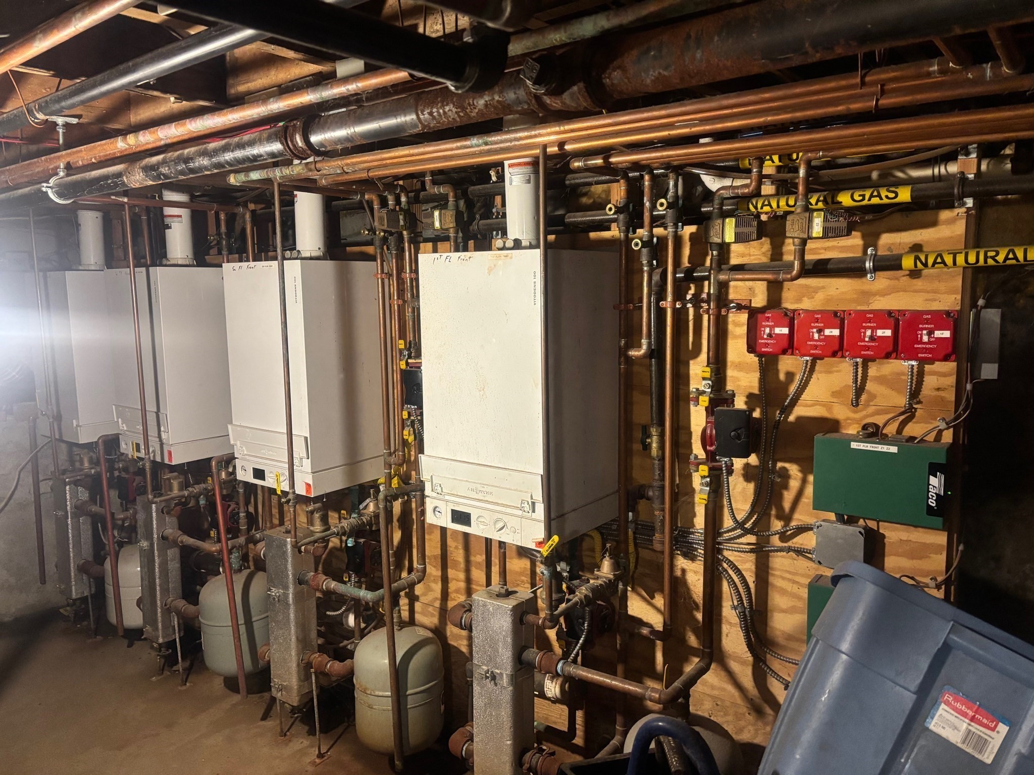 Mechanical room with multiple boilers, expansion tanks, and extensive exposed piping.