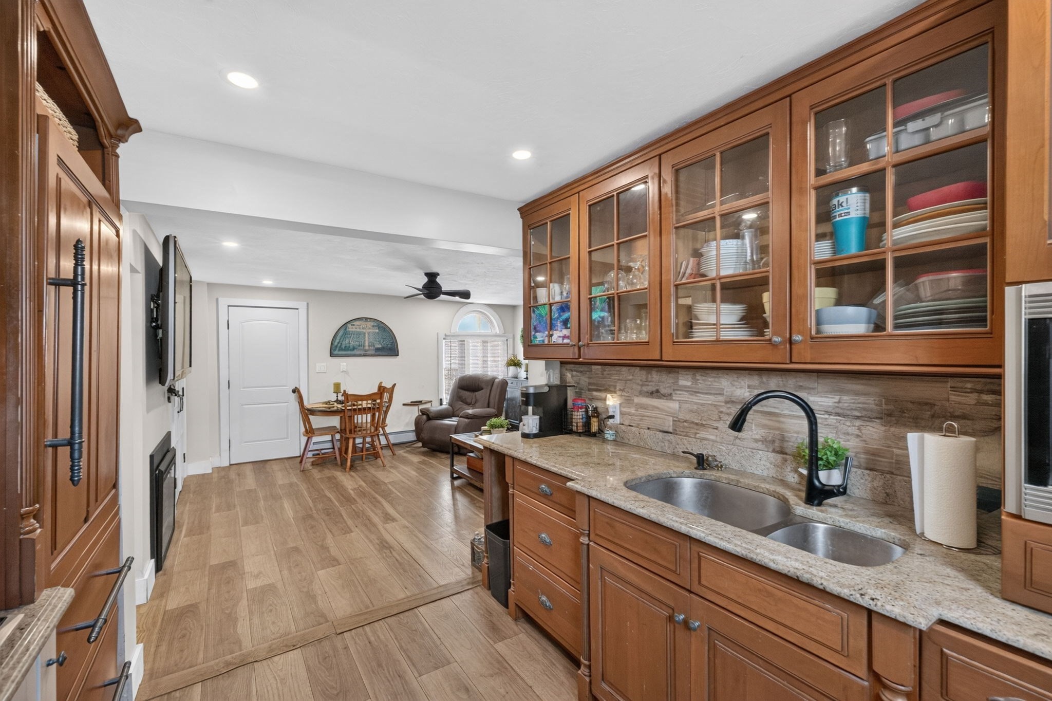 Kitchen with warm wood cabinetry, glass-front cupboards, granite counters, and a double-basin sink.