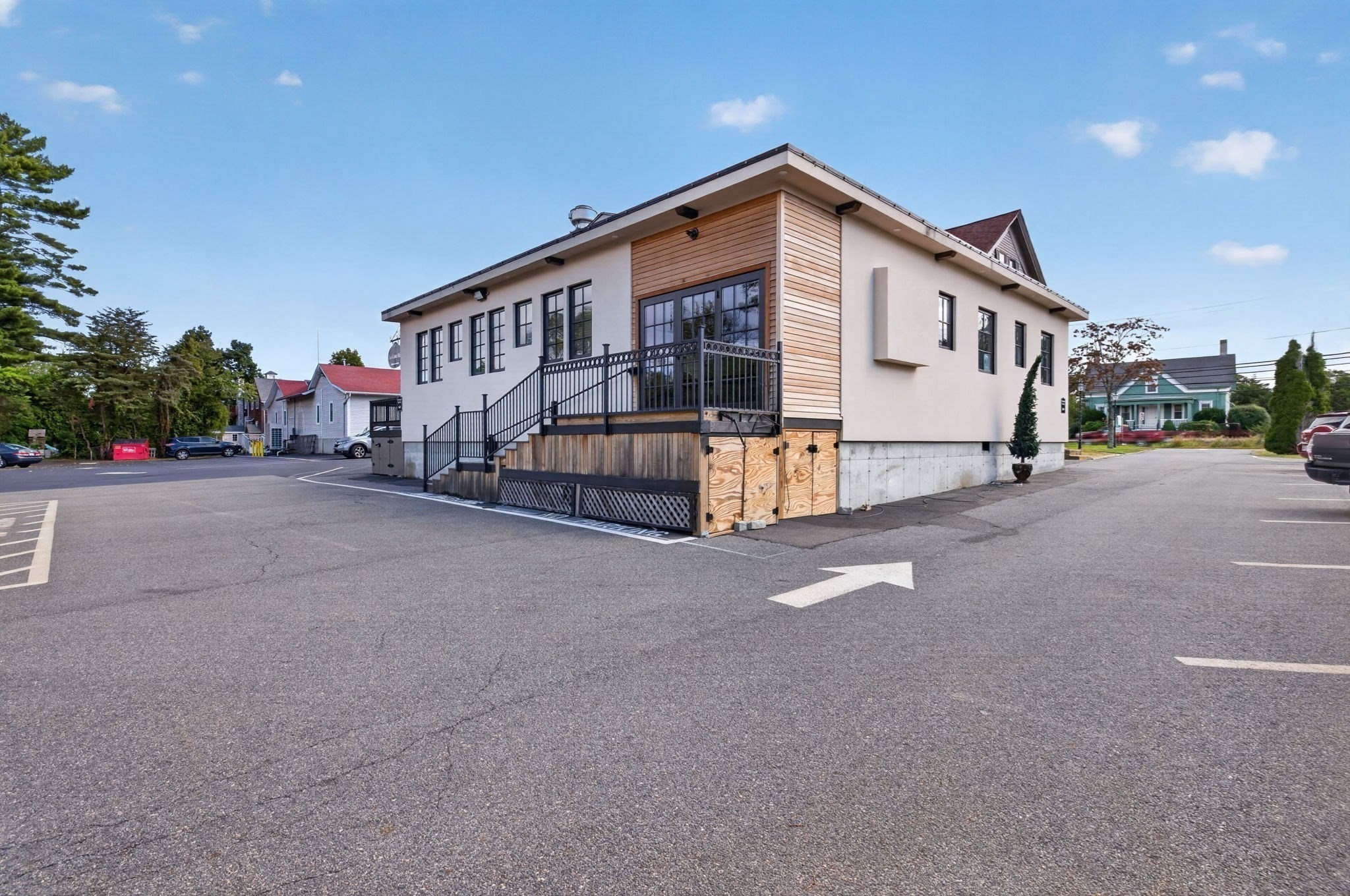 Commercial building with wood siding and a raised entrance deck beside a paved parking lot.