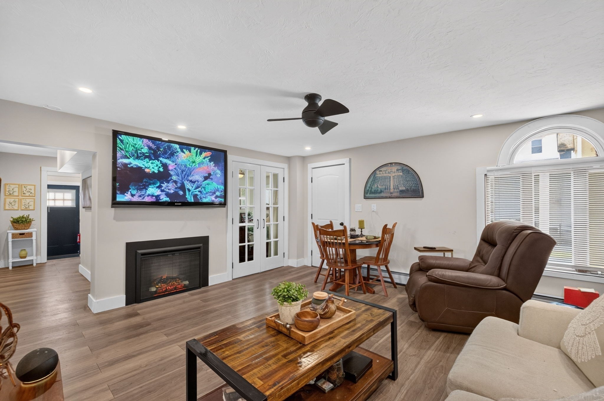 Living room with aquarium television, electric fireplace, dining nook, and brown recliner.