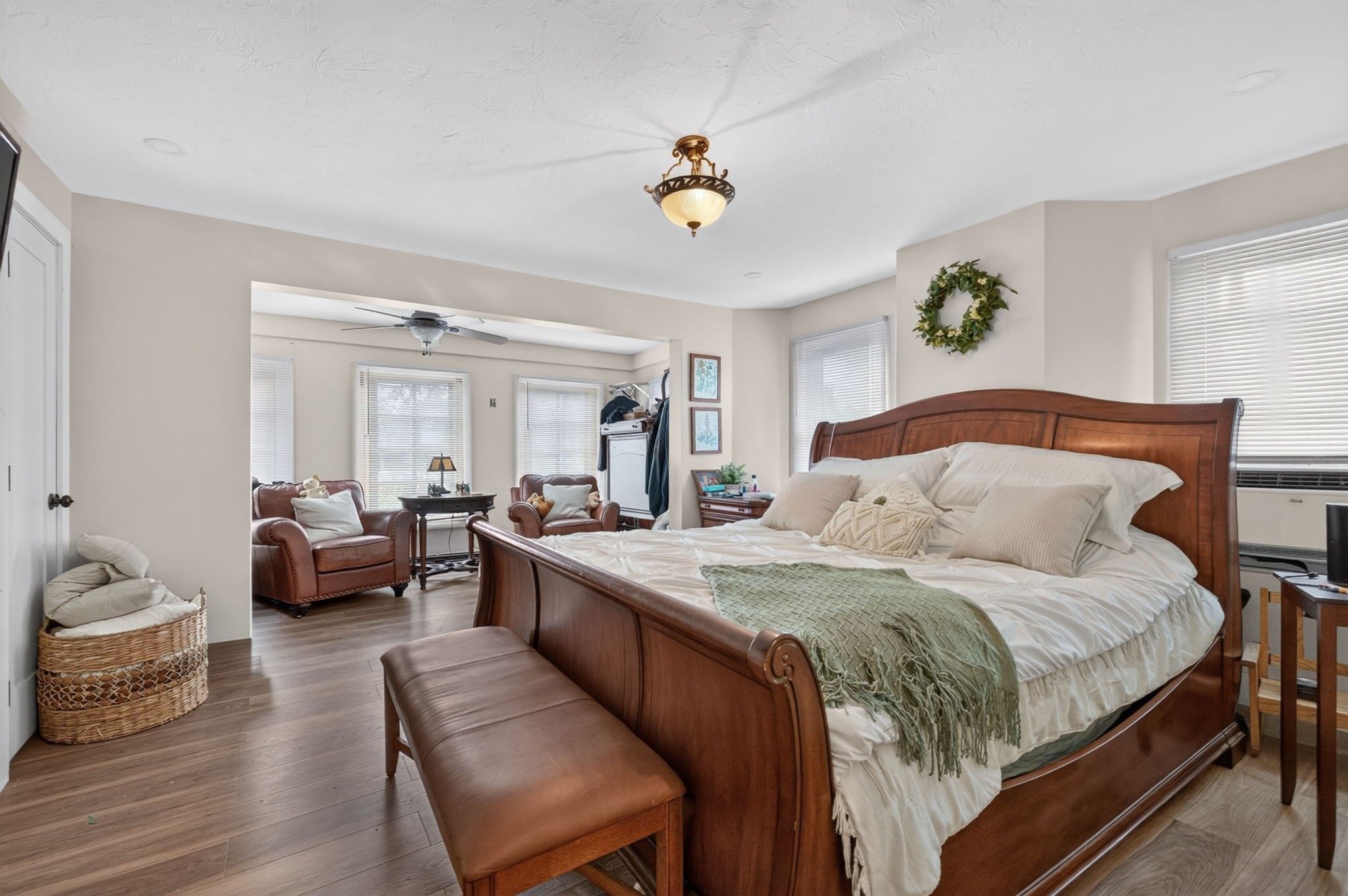 Bedroom with a wooden sleigh bed and an adjoining sitting area with leather chairs.