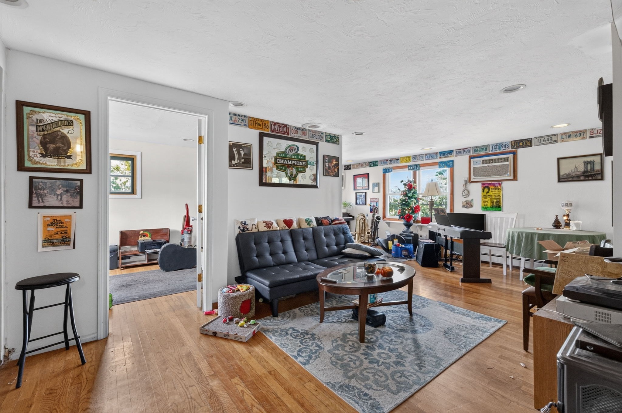 Living room with a black sectional, wall memorabilia, and a Christmas tree by the window.
