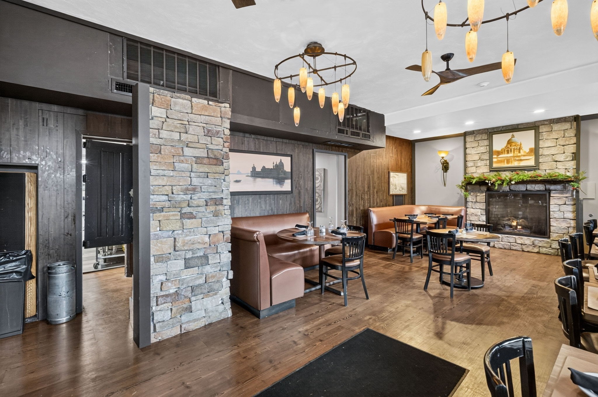 Dining area with a stone fireplace, leather booths, and round pendant lights.