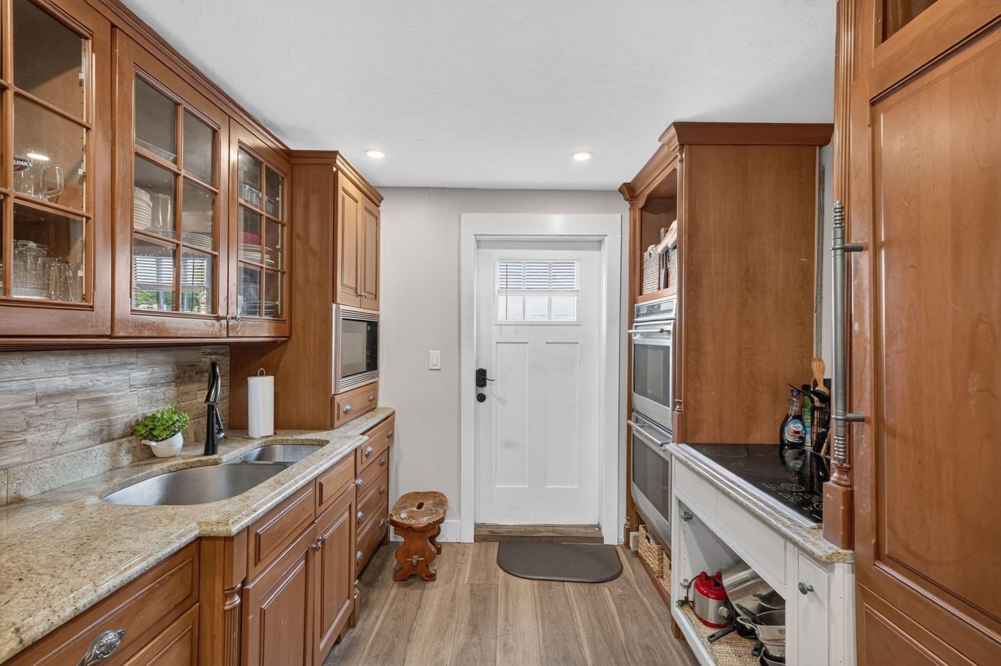 Kitchen with warm wood cabinetry, stone counters, and built-in double wall ovens.