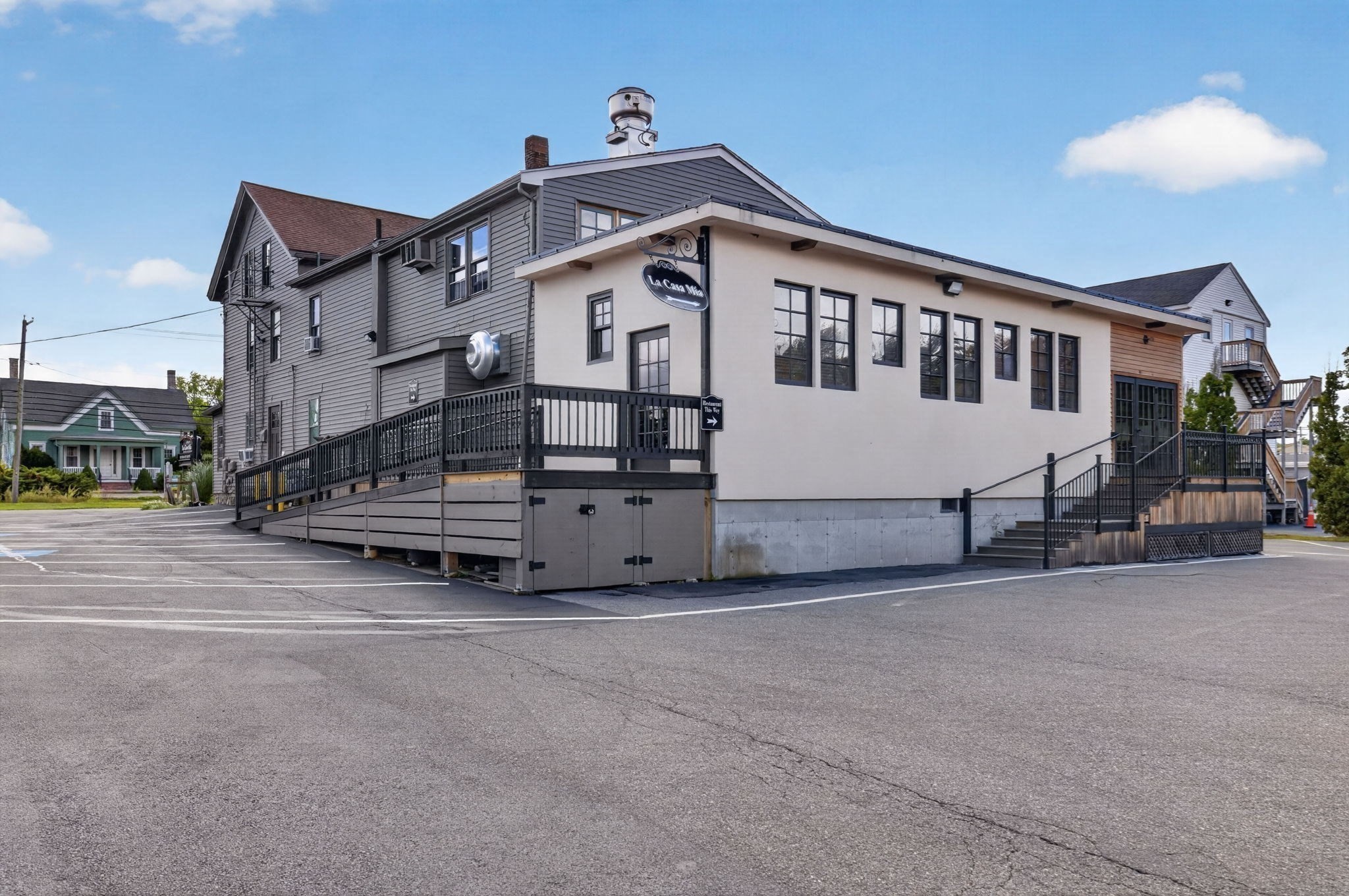 Commercial building with a raised entrance ramp, black railings, and a paved parking lot.