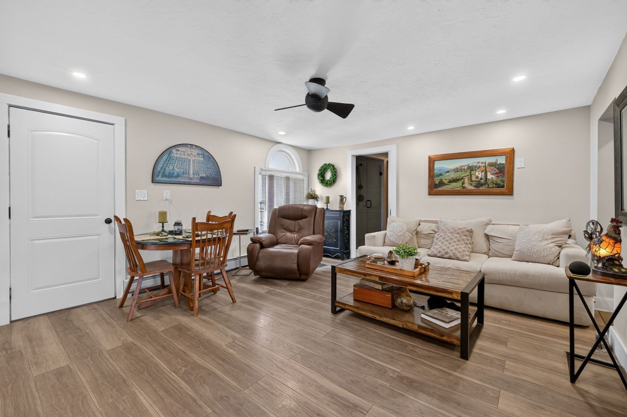 Living and dining area with a cream sofa, leather recliner, and wooden dining set.