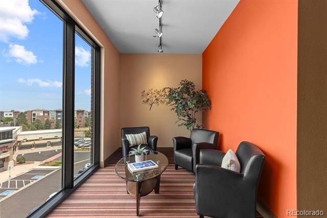 Furnished sitting area with black armchairs, a glass coffee table, and floor-to-ceiling windows.