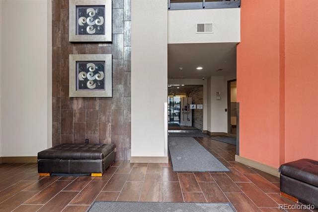 Building lobby with brown tile floors, a coral accent wall, decorative panels, and leather benches.