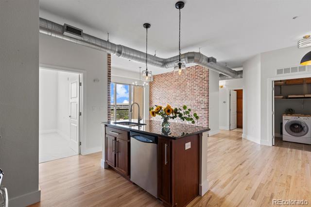 Open-plan kitchen with a dark wood island, exposed ductwork, and a red brick accent wall.