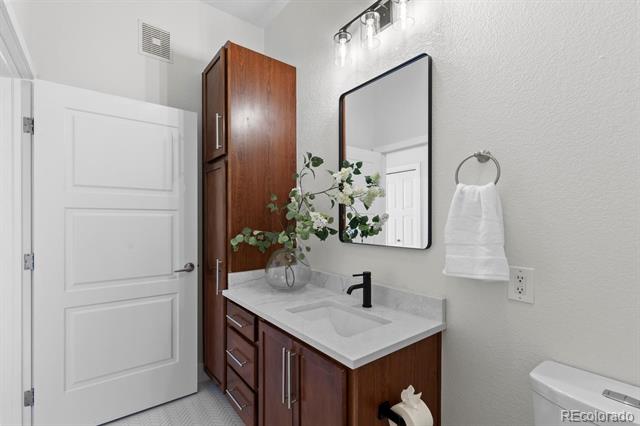 Bathroom vanity with a black faucet, dark wood cabinets, and a rectangular wall mirror.