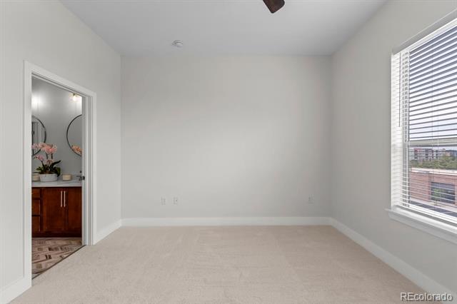 Unfurnished carpeted bedroom with a large window and an open doorway to the bathroom.