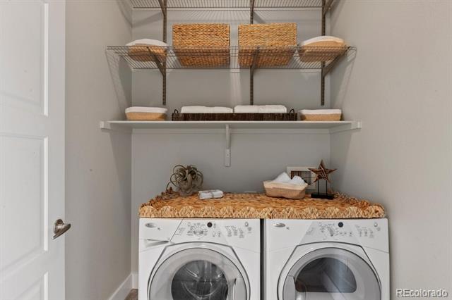 Laundry room with two front-loading washer-dryer units and open shelves above.