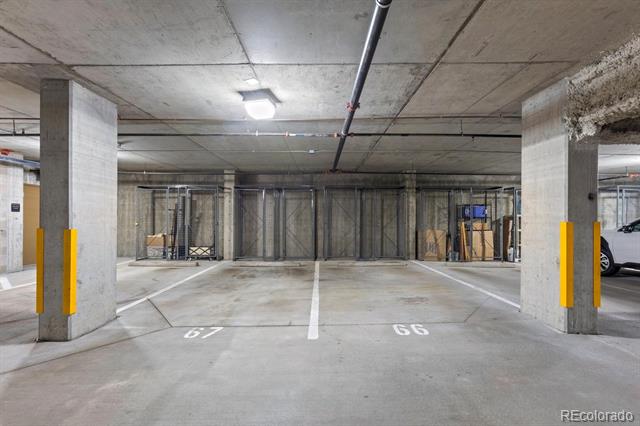 Underground parking garage with spaces 67 and 66 between concrete pillars with yellow guards.