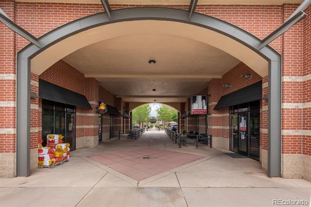 Brick commercial storefronts beneath a broad arched canopy along a covered pedestrian walkway.