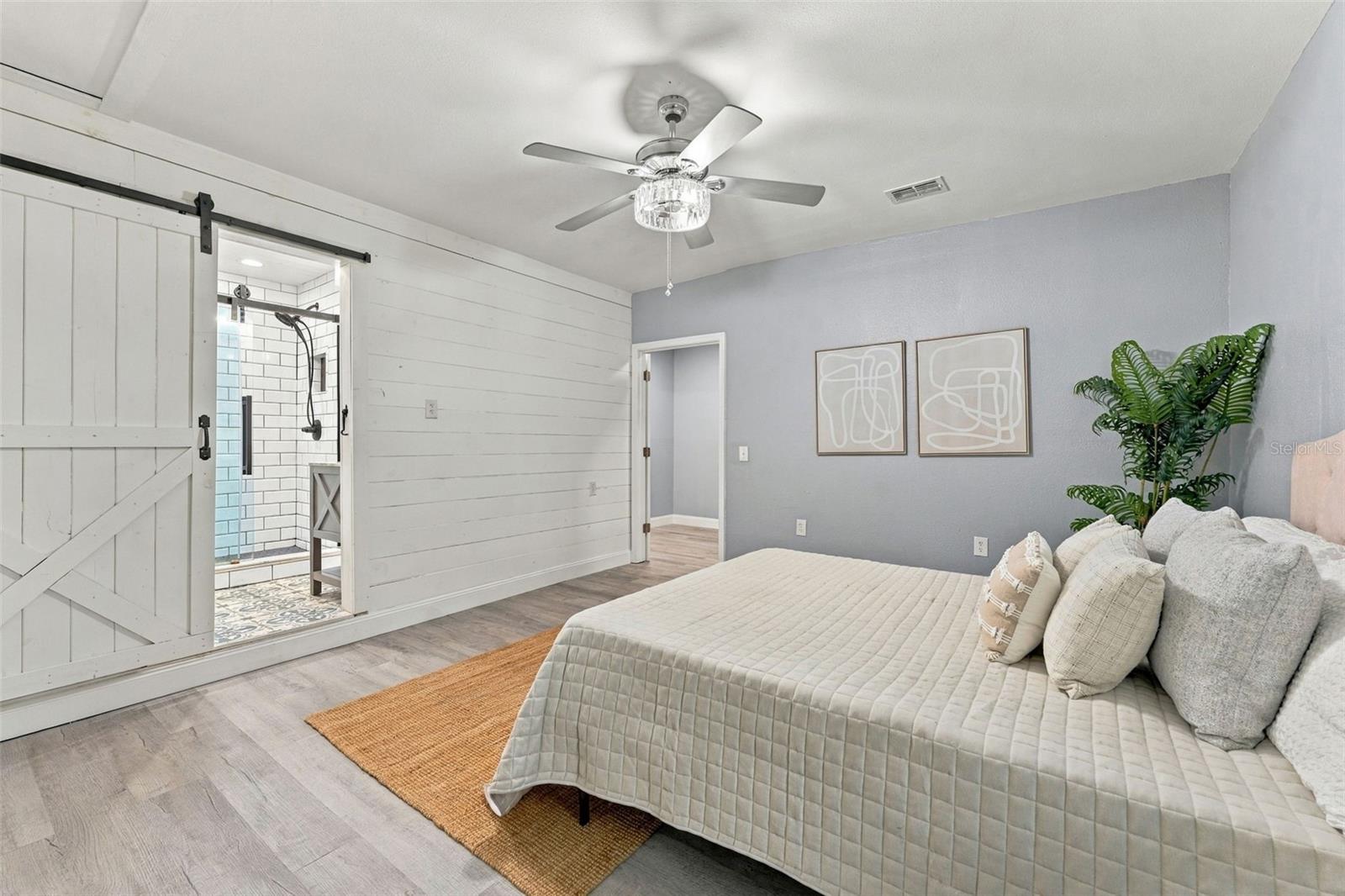 Bedroom with a white barn-style door opening to a tiled en-suite shower.