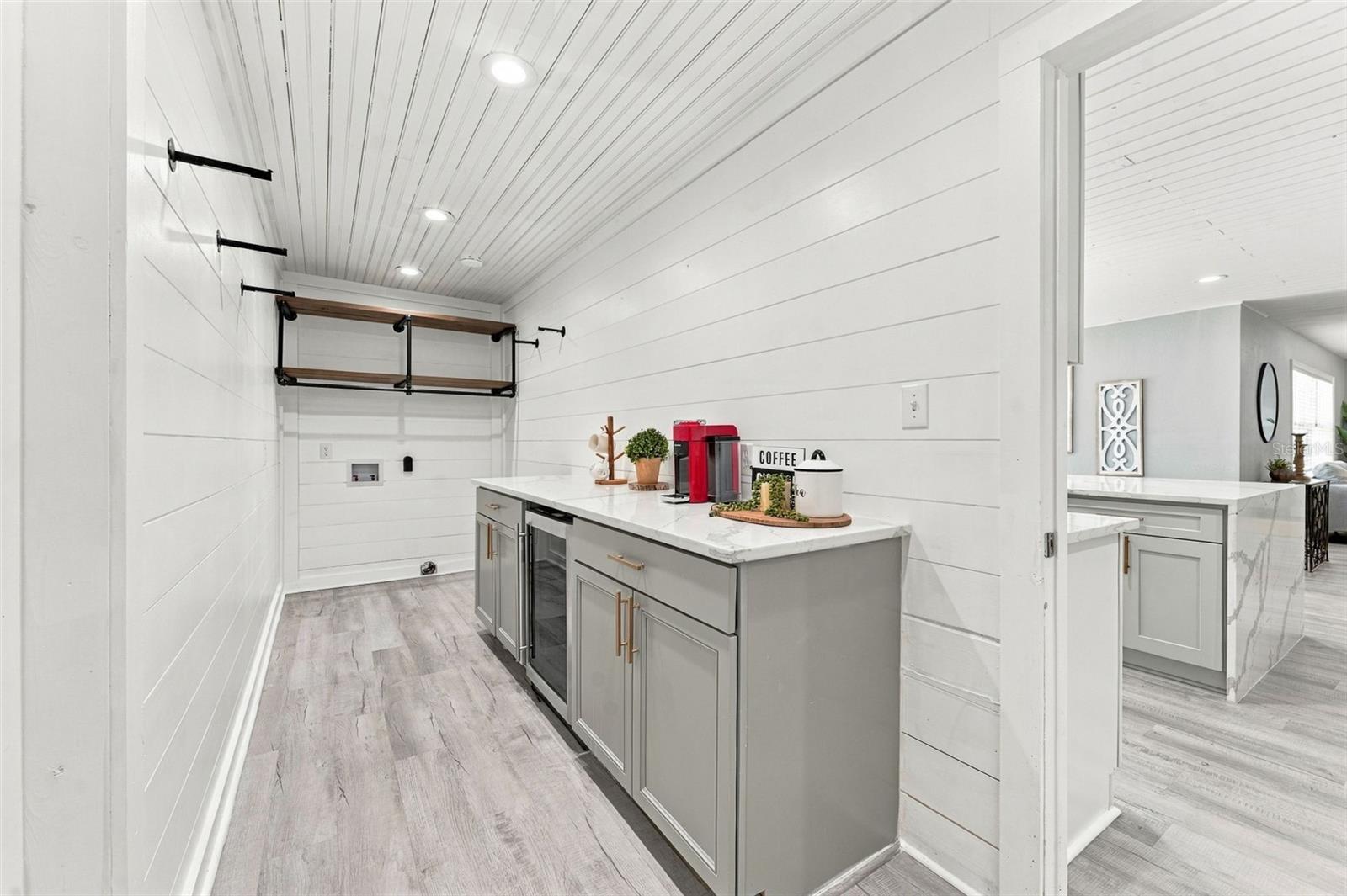 Coffee bar with gray cabinets, white countertop, red coffee maker, and open wood shelving.