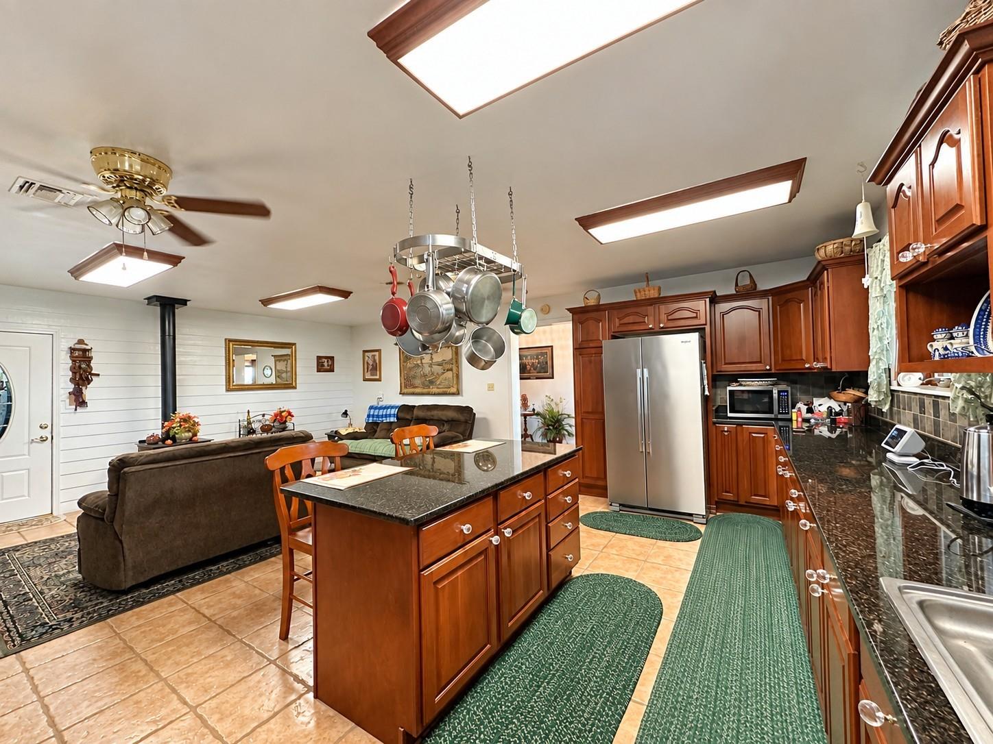 Kitchen with a wood island, hanging pot rack, stainless appliances, and an adjoining living area.