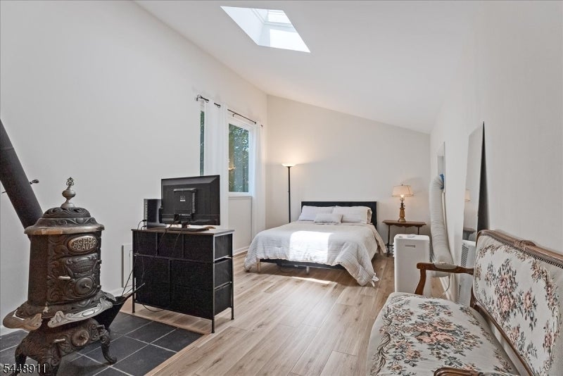 Attic bedroom with a skylight, a bed, a patterned sofa, and an ornate cast-iron stove.