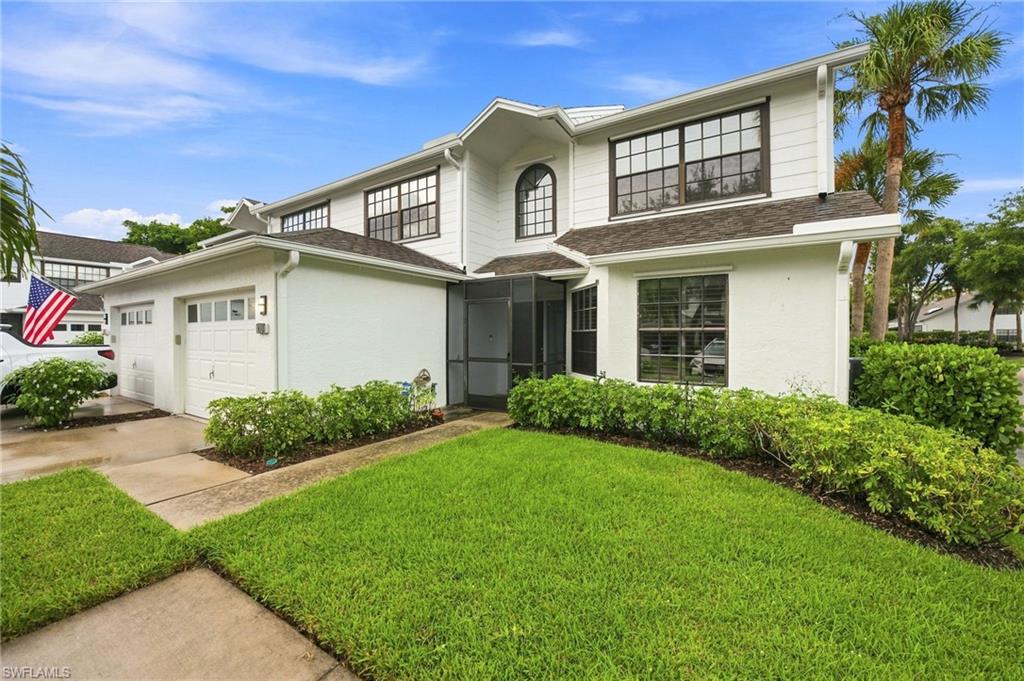 Two-story white home with dark-framed windows, double garage, screened entry, and manicured lawn.