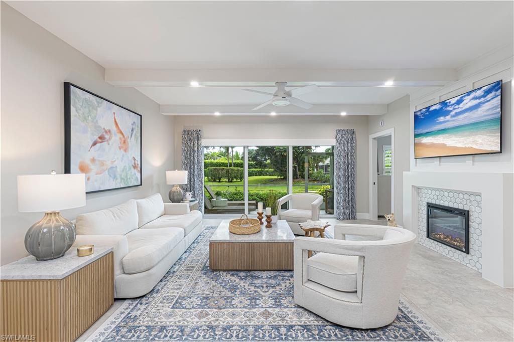 Living room with white seating, a tiled fireplace, and sliding doors overlooking a landscaped garden.