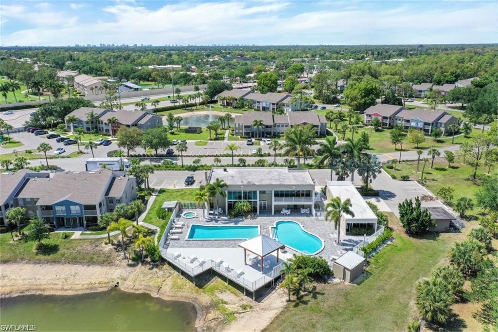 Aerial view of a residential community with a pool, recreation building, and pond.