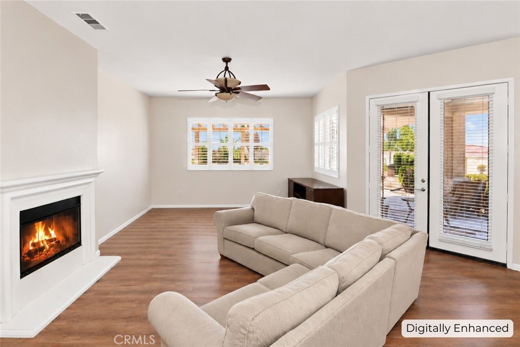 Living room with beige sofas, a lit fireplace, and glass doors opening to a patio.