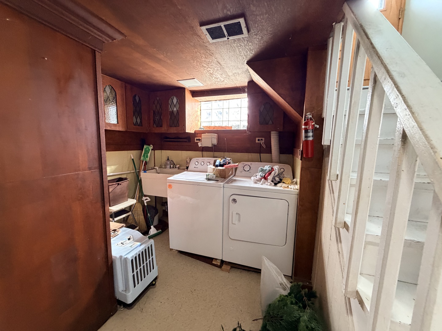 Basement laundry room with washer, dryer, utility sink, and built-in cabinets.