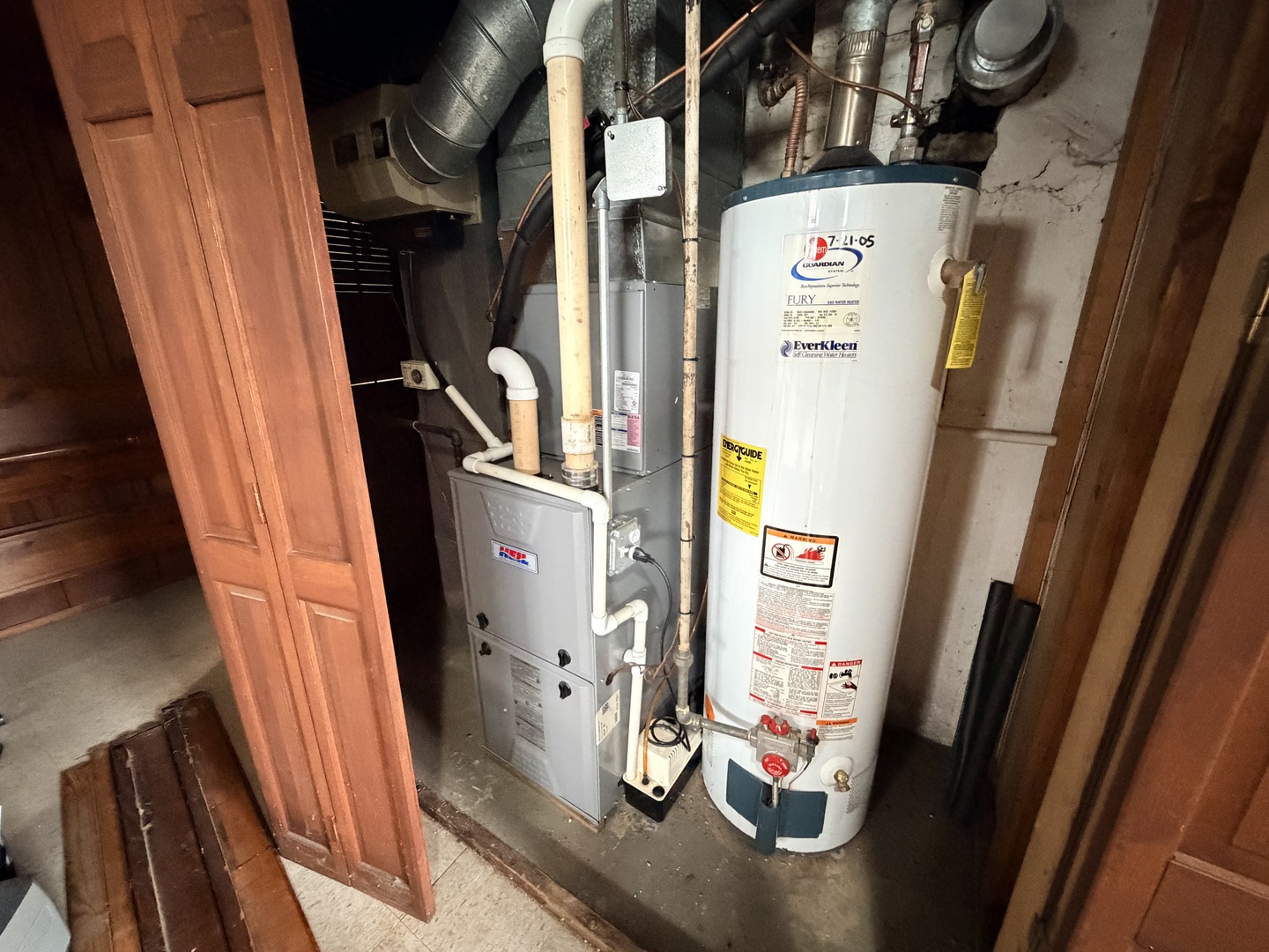 Utility room with a tall water heater beside a gray furnace and exposed ductwork.