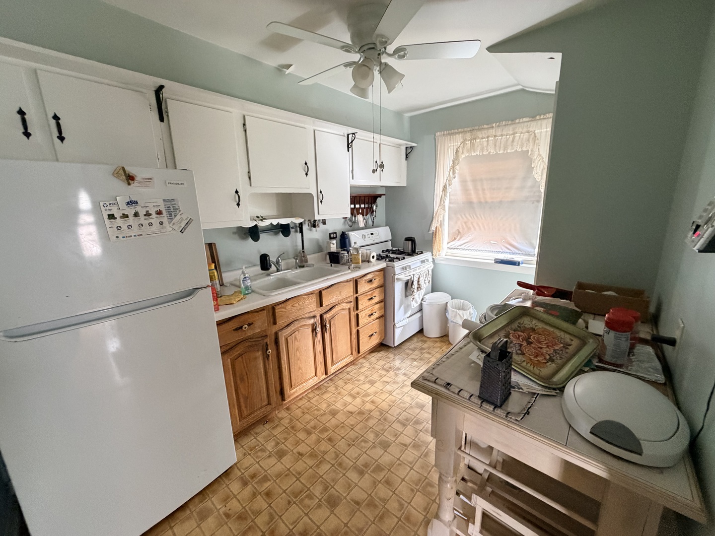 Kitchen with white upper cabinets, wood lower cabinets, and a ceiling fan.