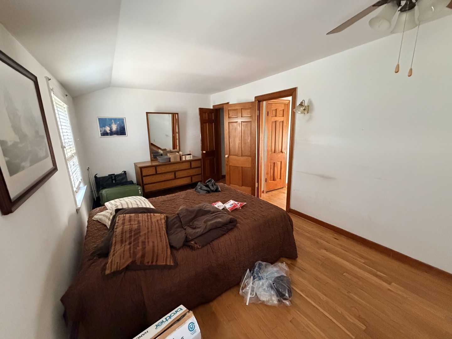 Bedroom with a brown-covered bed, hardwood floors, and several wooden doors.