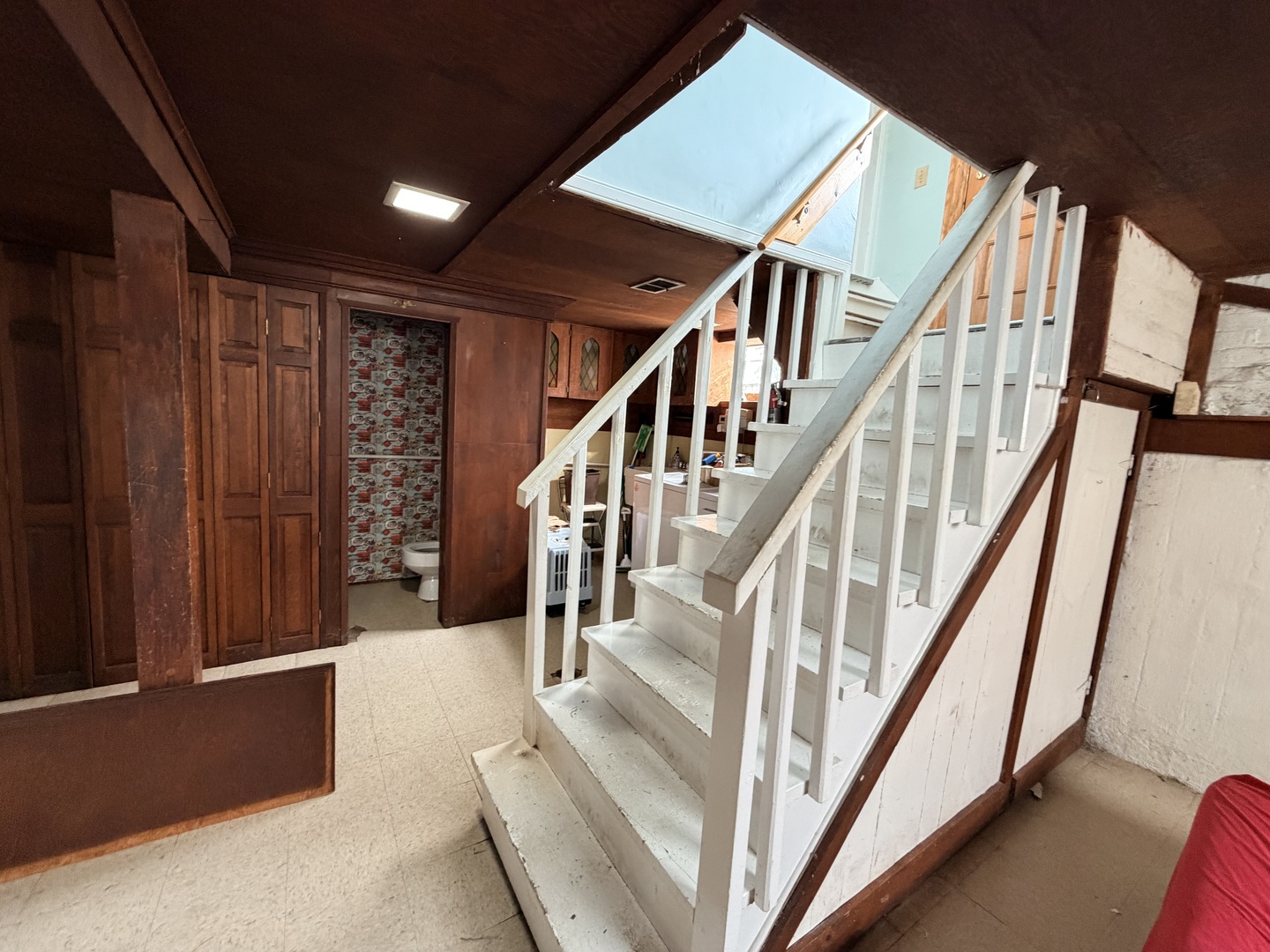 Interior staircase with white railings beside dark wood paneling and a skylight.