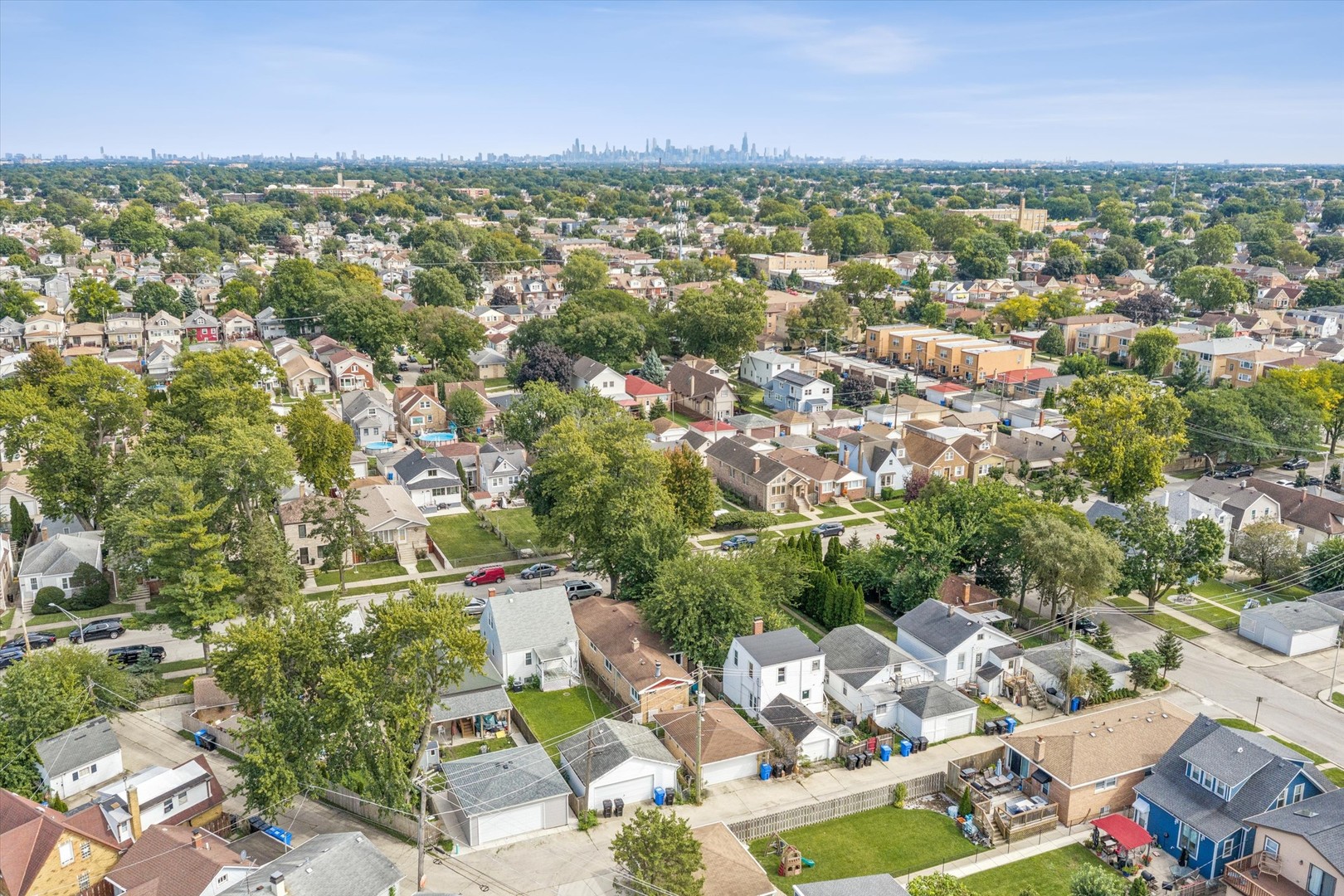 Aerial view of a leafy Chicago neighborhood with the downtown skyline in the distance.