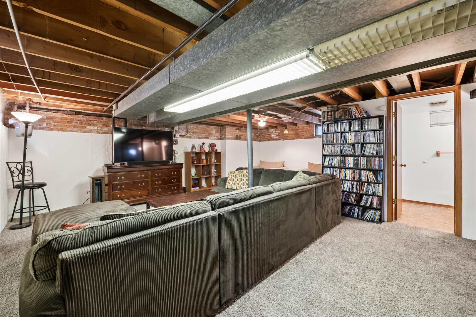 Basement family room with a large sectional sofa, television, and floor-to-ceiling shelves of DVDs.