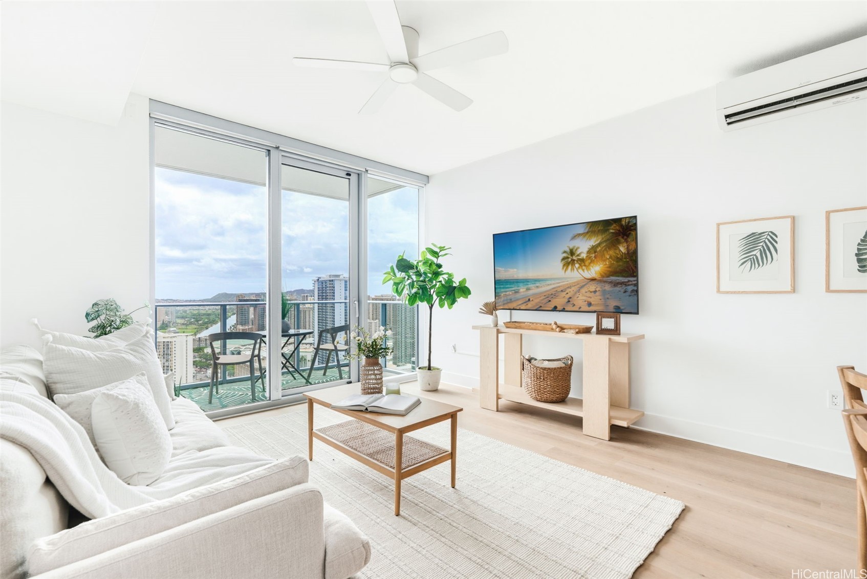 Bright living room with a white sofa and balcony doors overlooking Honolulu high-rises.