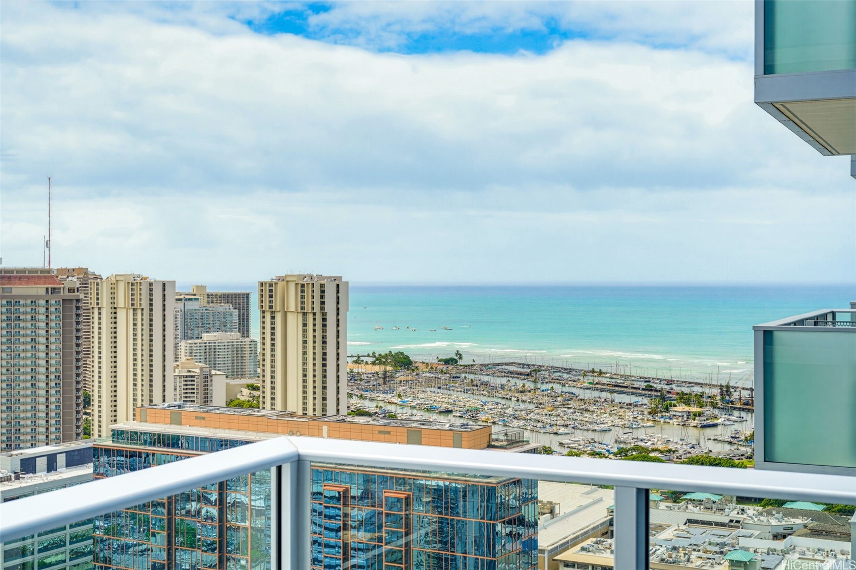 Balcony view over Waikiki high-rises, a crowded marina, and turquoise ocean.