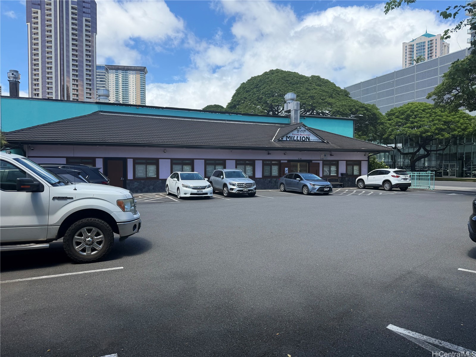 Korean restaurant exterior with a tiled roof, turquoise wall, and parked cars.
