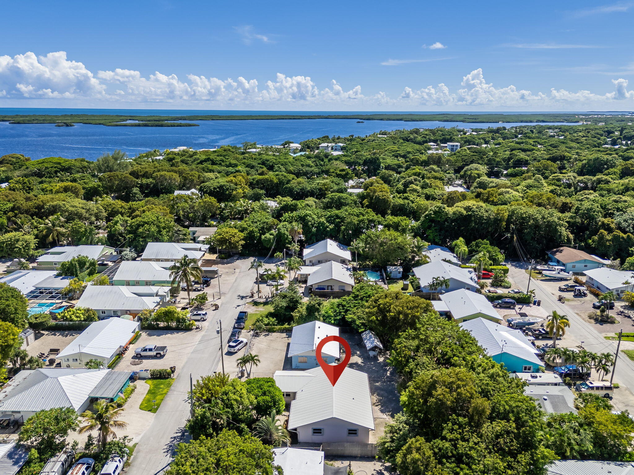 Aerial view of the marked home amid tropical houses, with broad blue waterways beyond.
