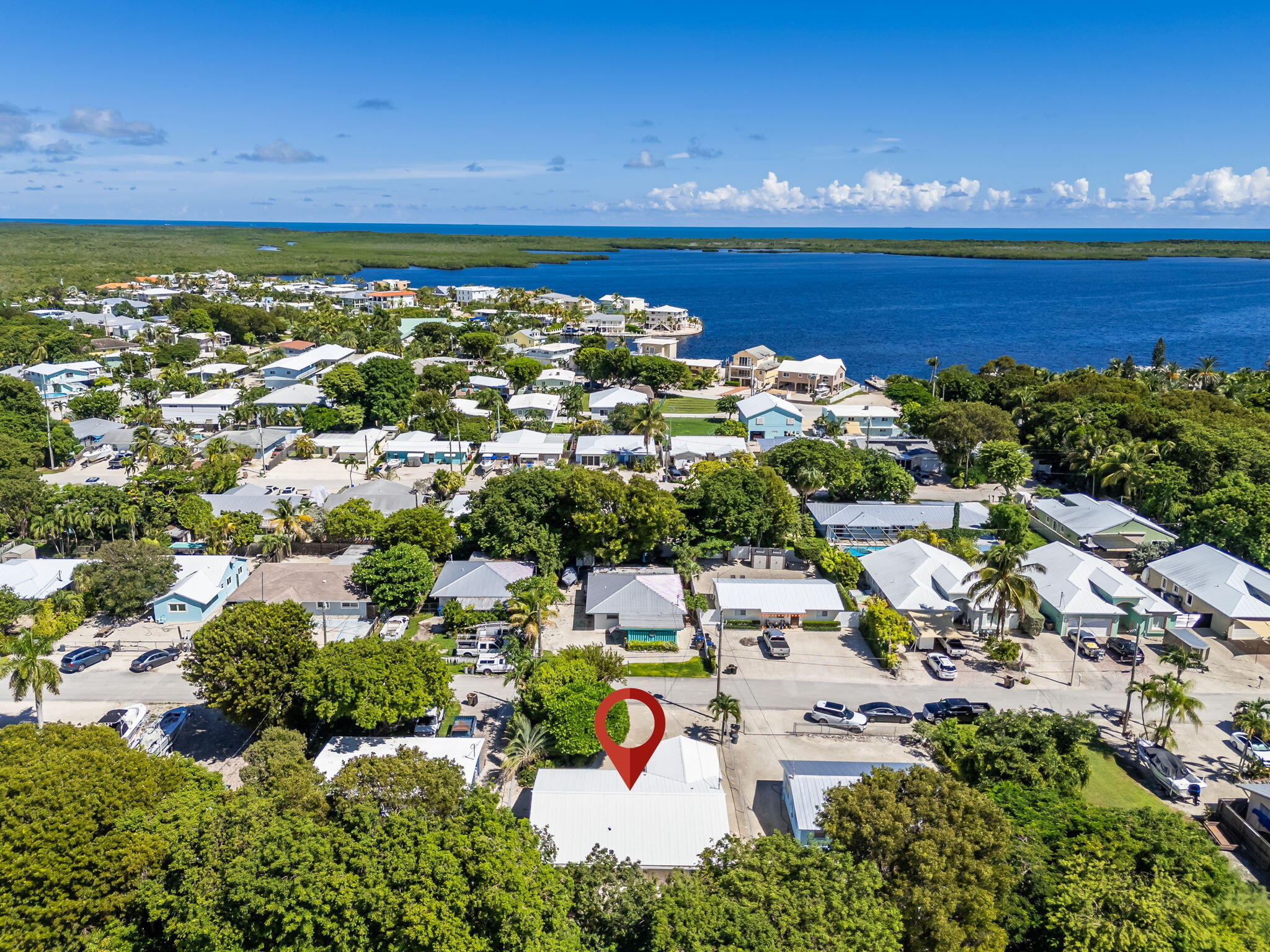 Aerial view of the marked home in a coastal neighborhood beside blue water.