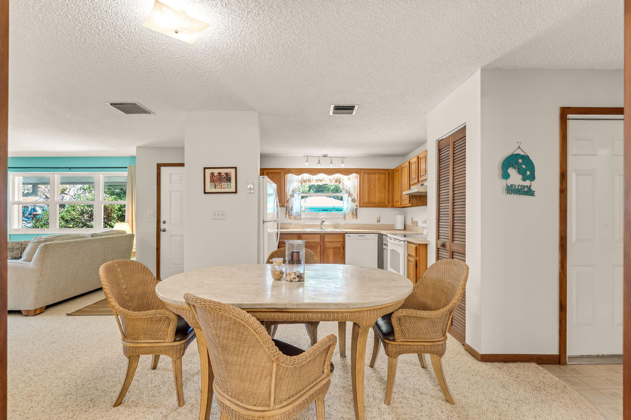 Dining area with a round table and wicker chairs beside a wood-cabinet kitchen.