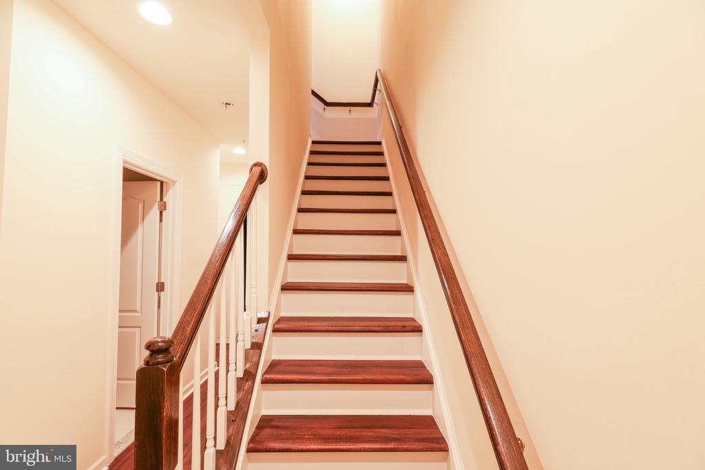 Staircase with dark wood treads and handrails, white risers, and a doorway beside it.