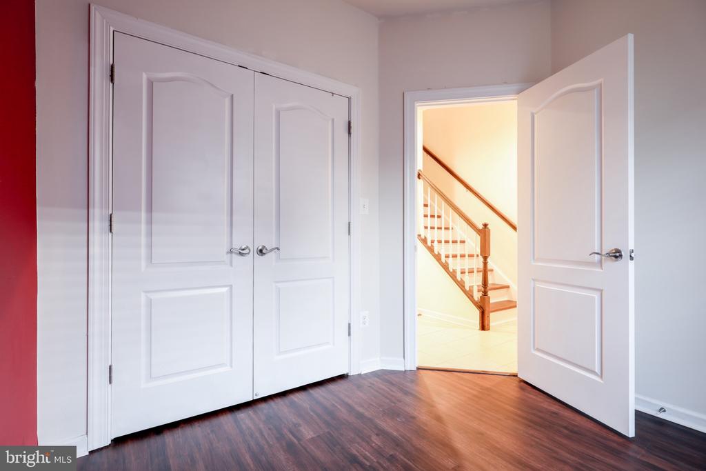 Empty interior with double closet doors and an open doorway revealing a staircase.