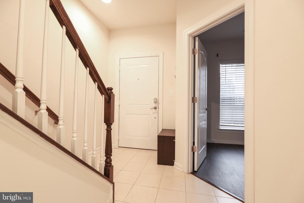 Entry foyer with a tiled floor and dark wood staircase beside the front door.