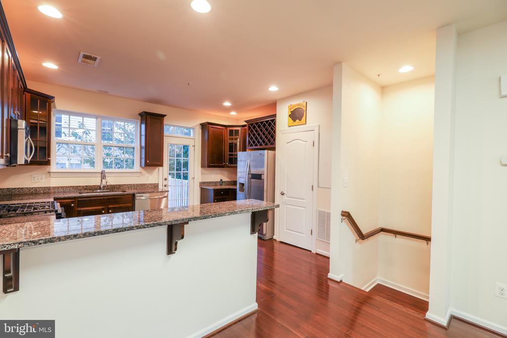 Kitchen with a granite peninsula, dark wood cabinets, and stainless steel appliances.