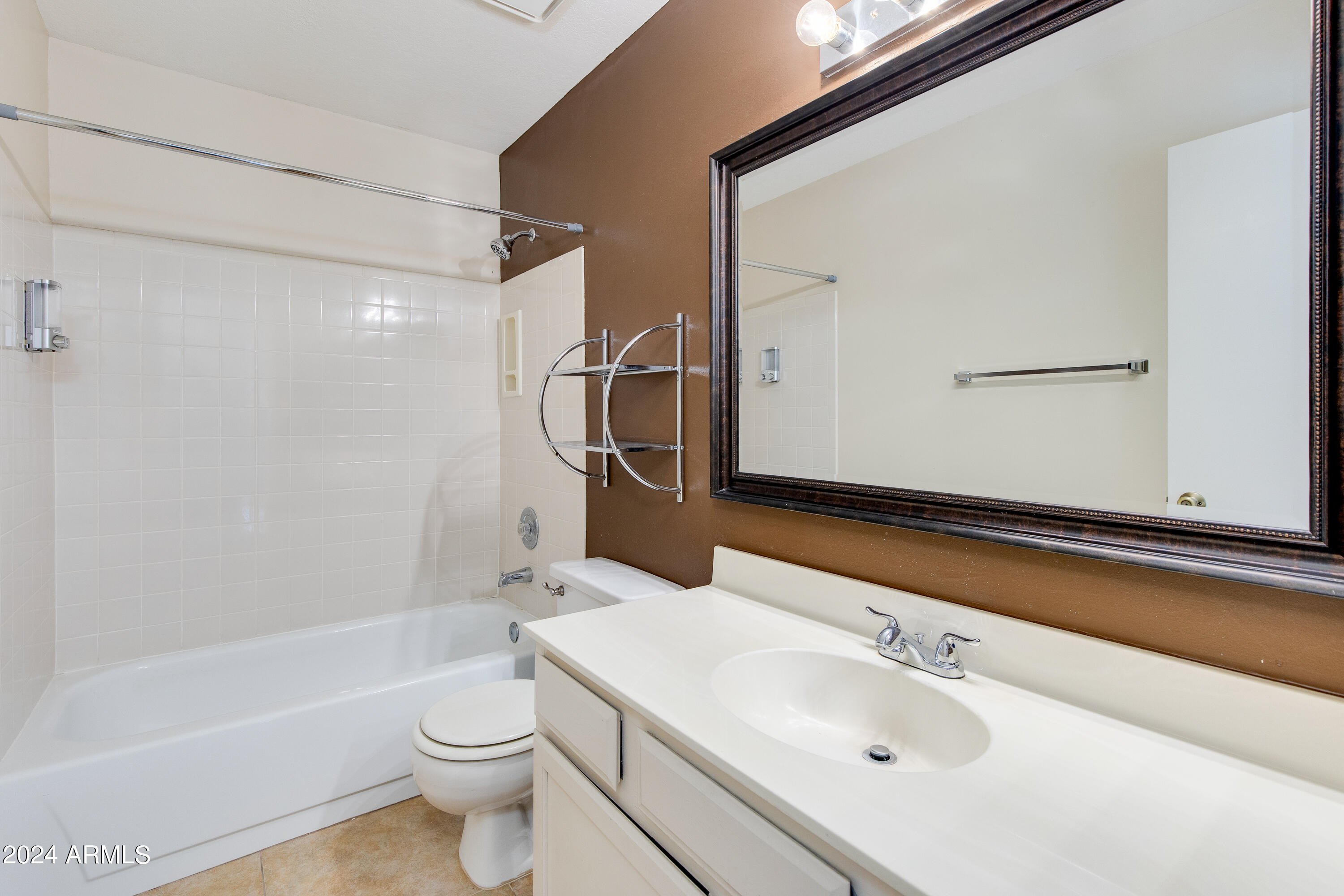 Bathroom with a white bathtub, tiled shower, toilet, and vanity beneath a large mirror.