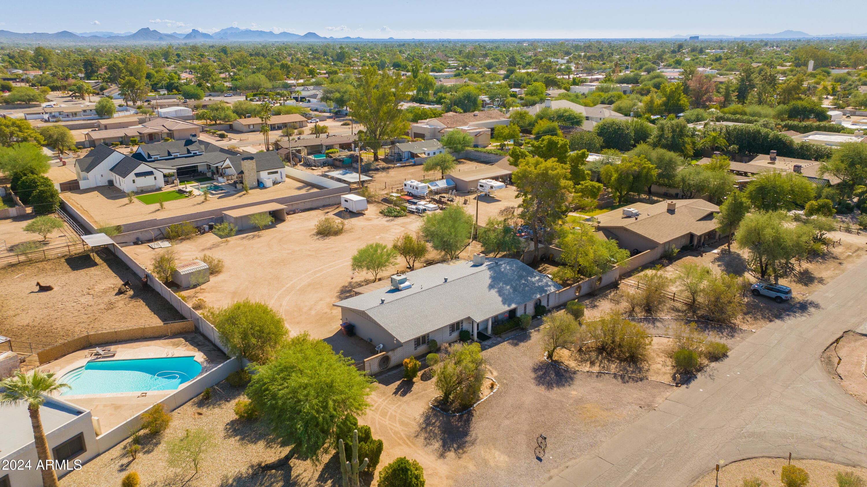 Aerial view of a Scottsdale home with a swimming pool, spacious lot, and distant mountains.