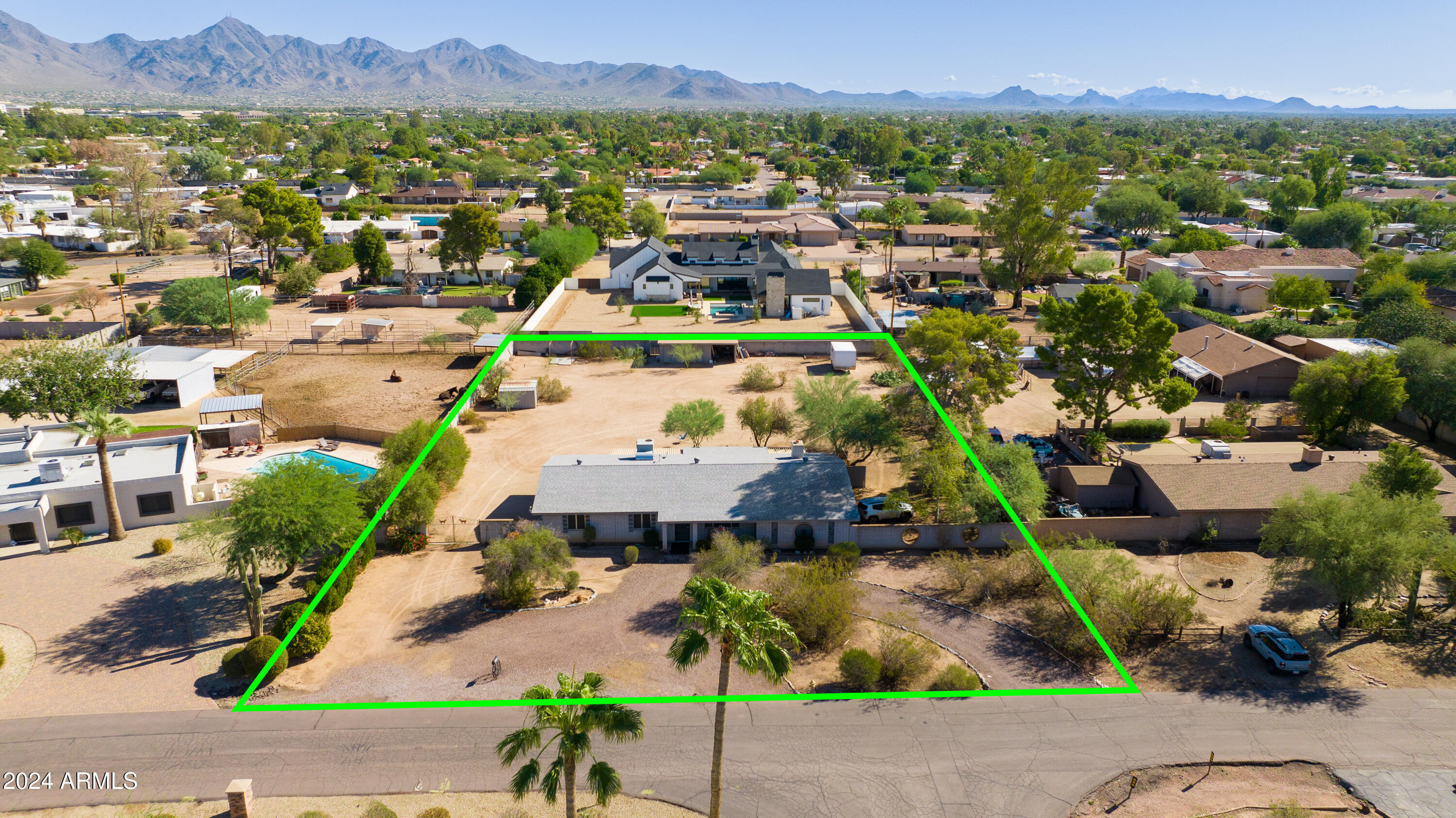 Aerial view of 13401 N 78th Street, a single-story home on a large lot outlined in green, with mountains beyond.