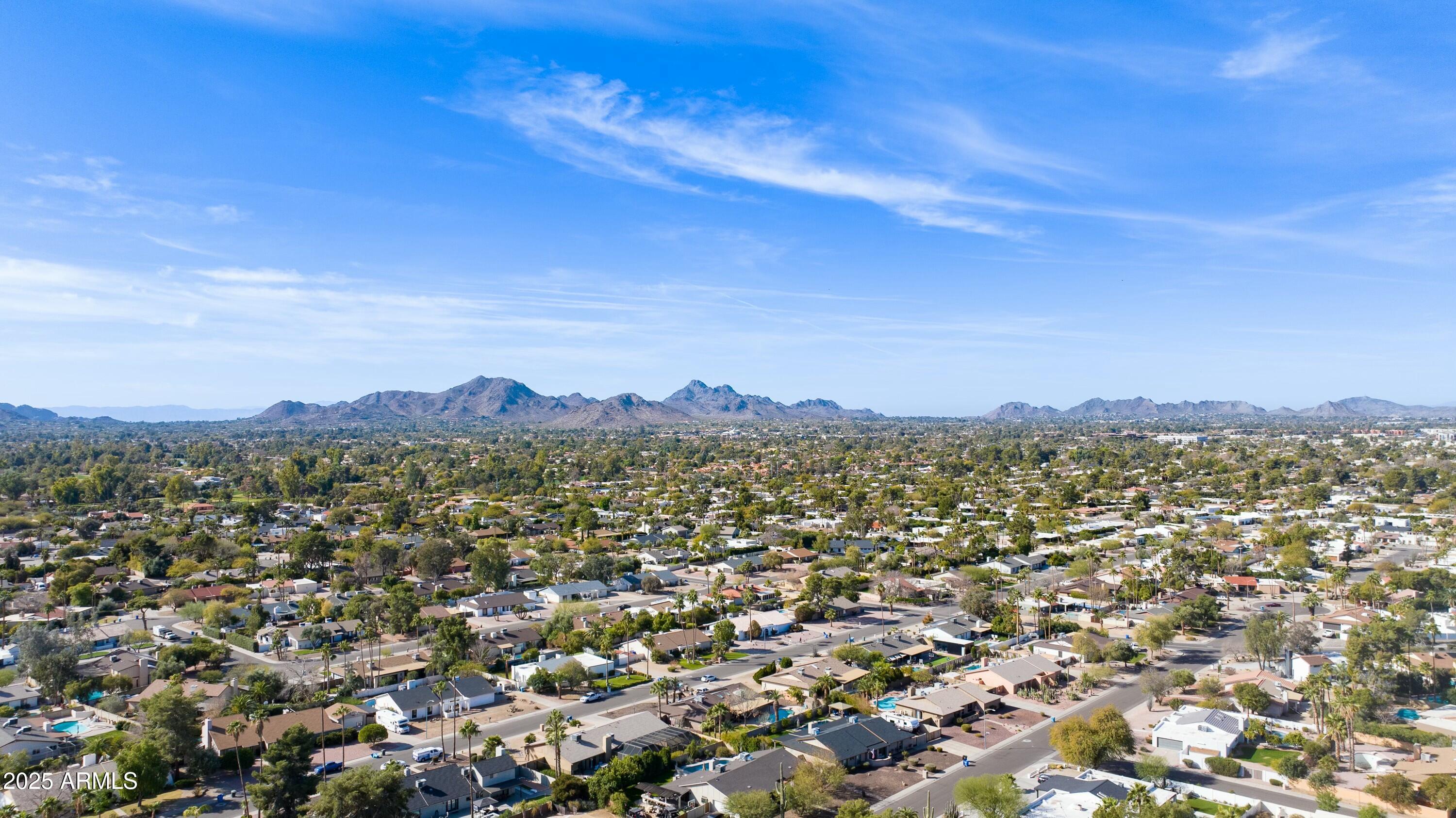 Aerial view of Scottsdale homes and tree-lined streets with desert mountains on the horizon.